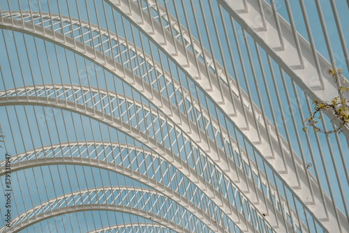 Detailed view of modern lattice arches with geometric patterns against a blue sky. The design highlights innovative architectural elements and structural elegance.