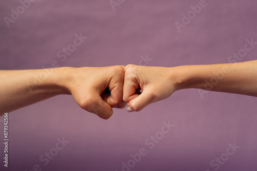 Beautiful female hand on isolated on purple background two hands fist to fist support sign language