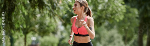 Fotografie A young woman with vitiligo runs through a park, wearing a pink sports bra and black leggings