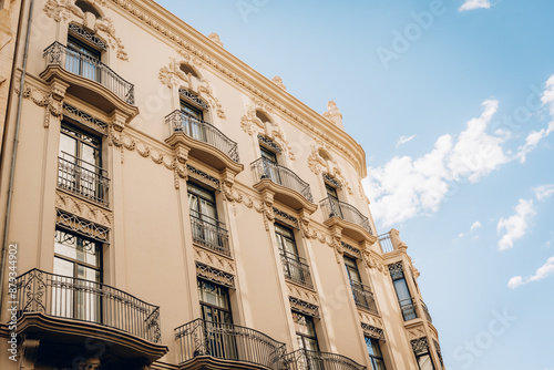 Low-angle view of an elegant historic building in Valencia with ornate balconies and detailed architectural elements, capturing the beauty of Spanish heritage under a clear sky.