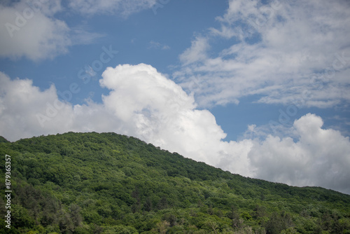 Nature, forested mountains, blue sky with white clouds.