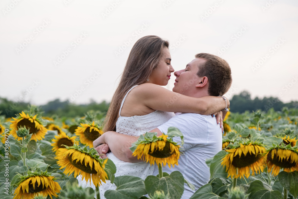 Cheerful couple in sunflowers in field at sunset Cheerful couple in sunflowers in field at sunset