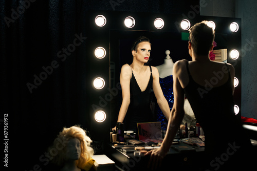 Obraz na płótnie A drag queen prepares backstage, adjusting her outfit while looking in the mirror