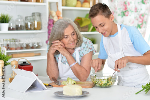 Grandmother and grandson preparing salad in the kitchen