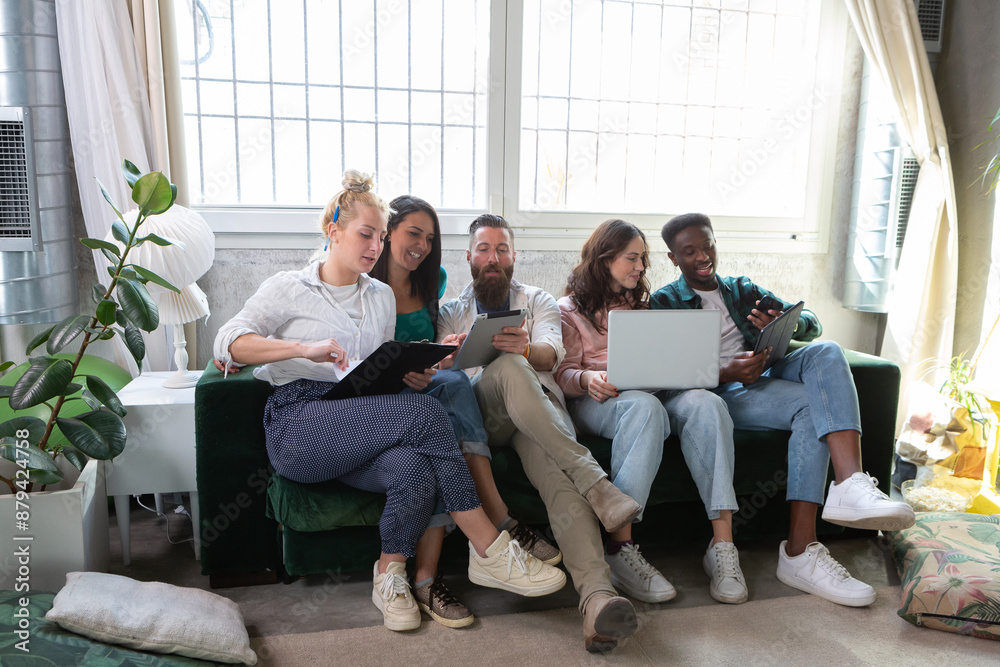 Group of young people using digital devices on sofa at home Group of young people using digital devices on sofa at home