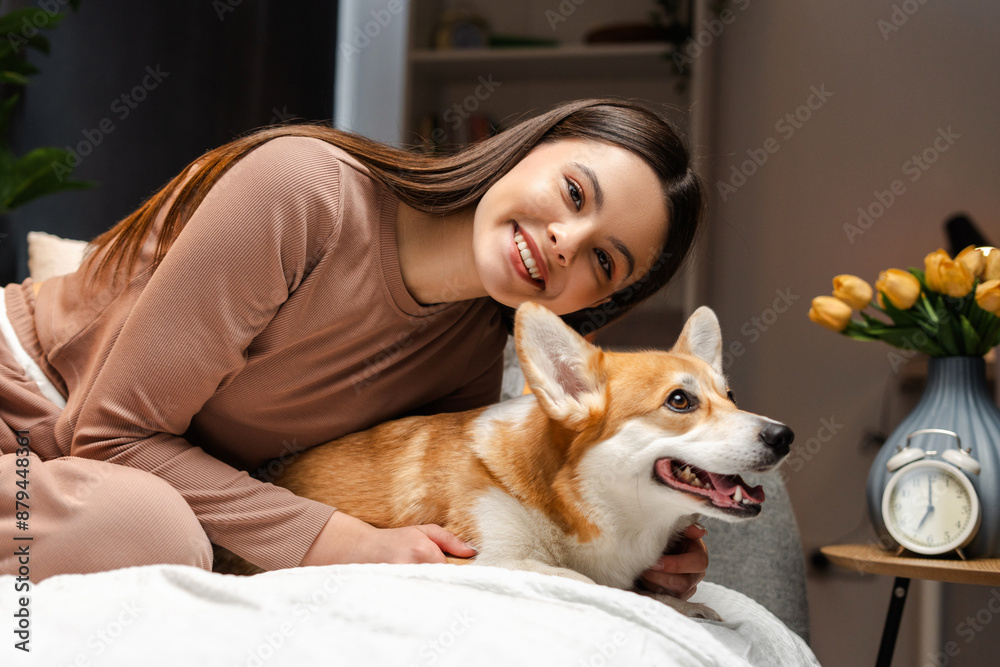 Happy young teenager relaxing on bed with corgi dog Happy young teenager relaxing on bed with corgi dog