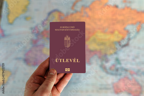 Man holding Hungary passport in hand and world map in background