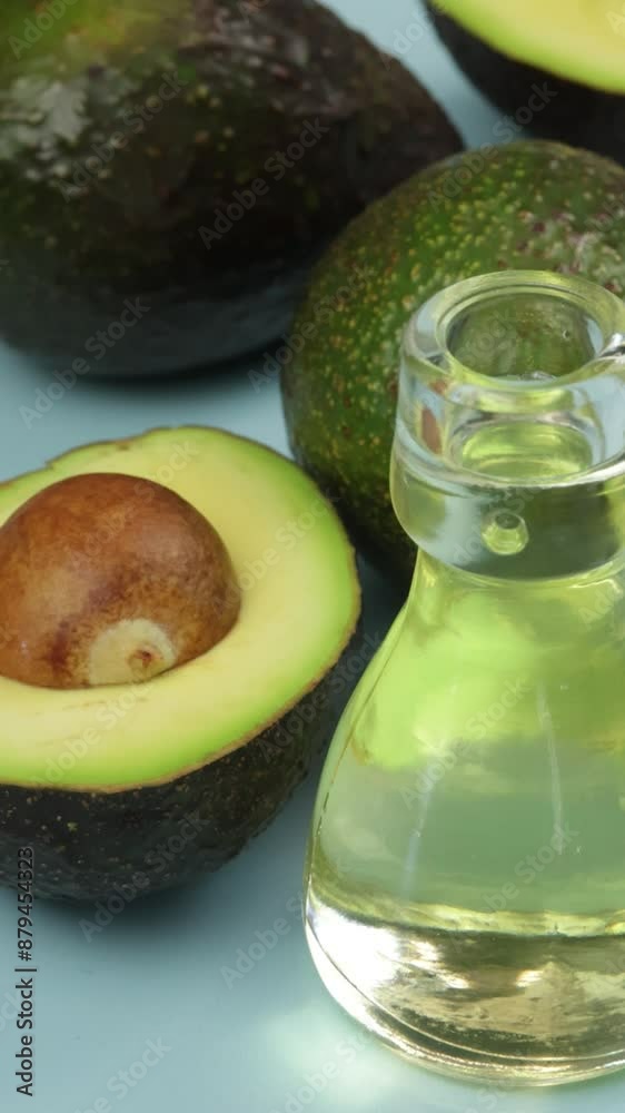 avocats et petite bouteille en verre d'huile, en gros plan, sur un fond bleu