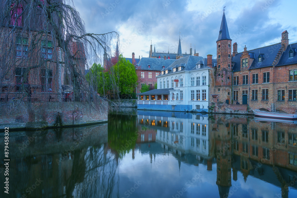 Fototapeta premium Most popular view of Old Town of Bruges from Rozenhoedkaai (Rosary quay), Belgium. Scenic cityscape with medieval historical buildings along the Dijver canal at sunset, outdoor travel background