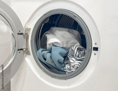 load laundry into the washing machine. wash dirty linen