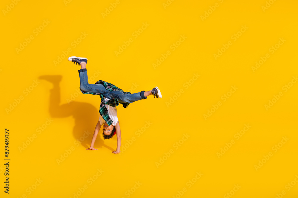 Full body photo of cute little boy upside down handstand dressed stylish white clothes isolated on yellow color background Full body photo of cute little boy upside down handstand dressed stylish white clothes isolated on yellow color background
