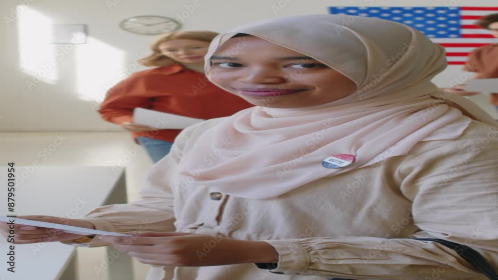 Vertical portrait shot of smiling muslim girl in hijab holding paper ballot and posing for camera at polling place Vertical portrait shot of smiling muslim girl in hijab holding paper ballot and posing for camera at polling place