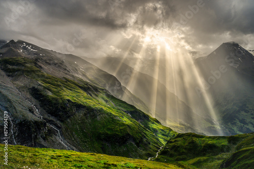Nature and landscape in the spring. Landscape with dramatic sky and green meadows. The sun rays through the clouds. The Hohe Tauern mountain range, the valley below the hochalpenrstrasse.