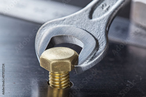 Wrench tightens bolt in steel billet. Spanner, bolt, screw and nuts.