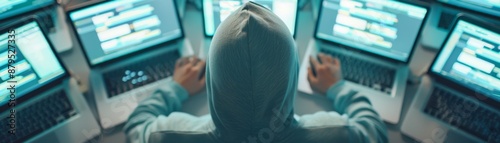 Person in Hoodie Working on Multiple Laptops in Dark Room