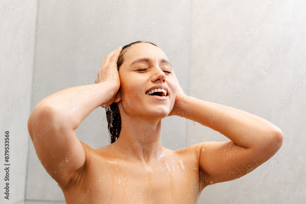 Naklejka premium Young happy woman taking care of her skin while taking hot shower at modern home