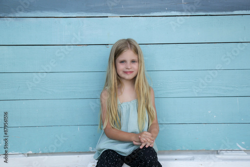 Candid portrait of cute 7 years old girl witl long blonde hair and linen shirt photo