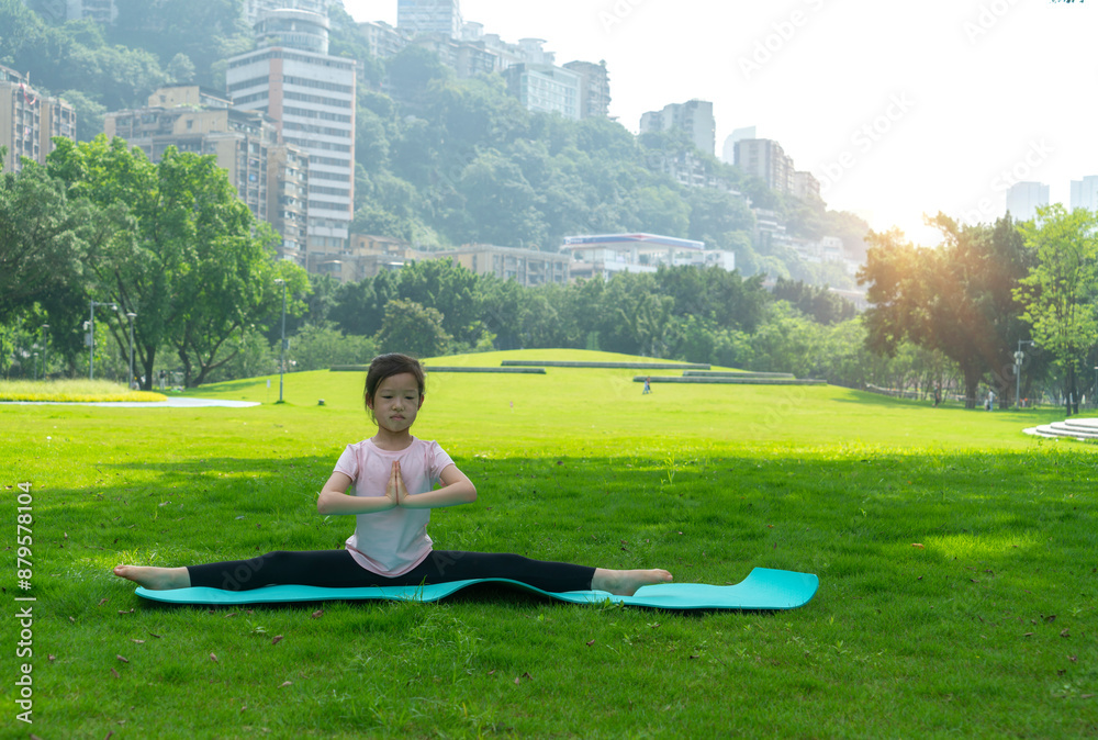 A cute little girl doing yoga on the park grass A cute little girl doing yoga on the park grass