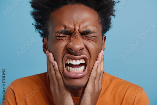 A man with a black afro is in pain and clenching his teeth. Concept of discomfort and distress