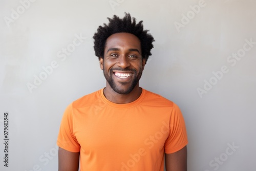 Portrait of a grinning afro-american man in his 30s wearing a moisture-wicking running shirt in front of minimalist or empty room background