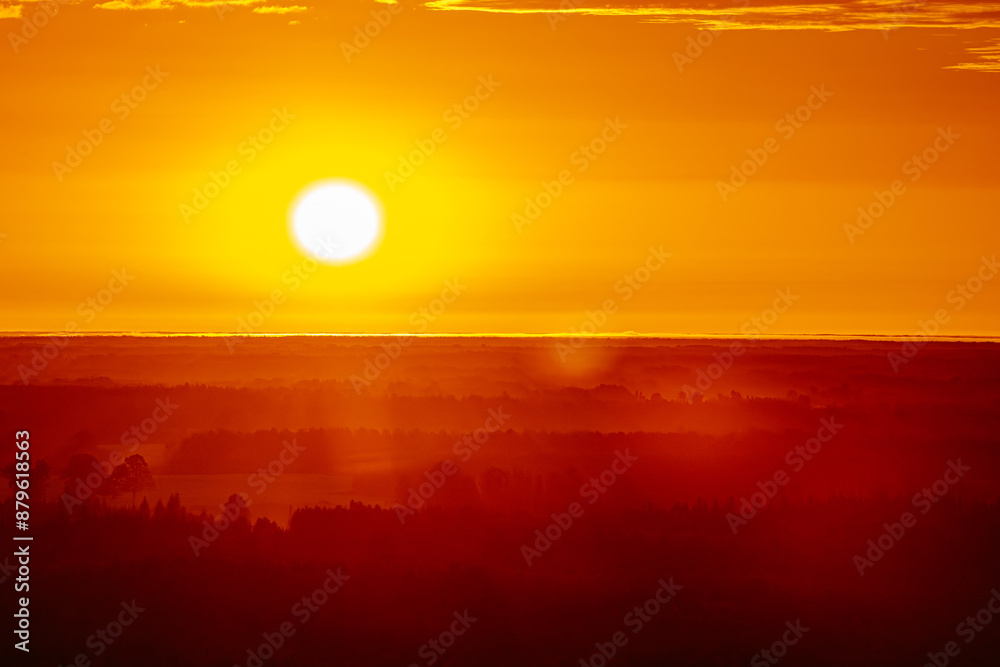A radiant sunset over a forested horizon, with the sun casting a warm, golden glow across the sky and landscape. The vibrant orange and yellow hues create a stunning and tranquil scene. Copy space. A radiant sunset over a forested horizon, with the sun casting a warm, golden glow across the sky and landscape. The vibrant orange and yellow hues create a stunning and tranquil scene. Copy space.