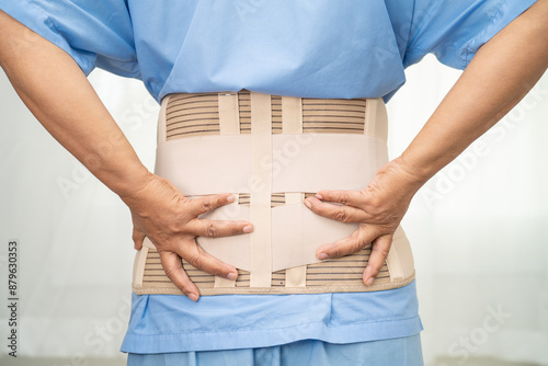 Asian lady patient wearing back pain support belt for orthopedic lumbar with walker. photo