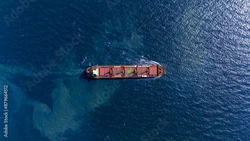 Aerial top view large general cargo ship bulk carrier running hi-speed in the deep sea.