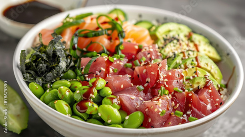 Fresh tuna and salmon poke bowl with edamame, avocado, seaweed, and rice, topped with sesame seeds