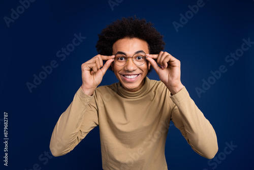 Photo portrait of handsome young man look camera touch specs dressed stylish beige garment isolated on dark blue color background