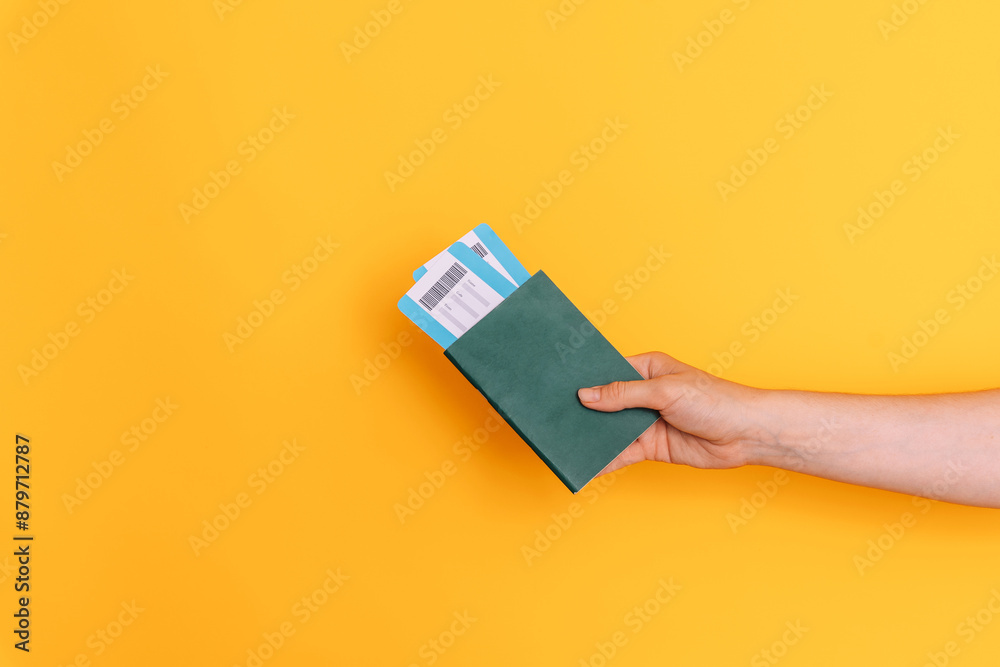 Hand holding a passport with tickets against a yellow background. Hand holding a passport with tickets against a yellow background.