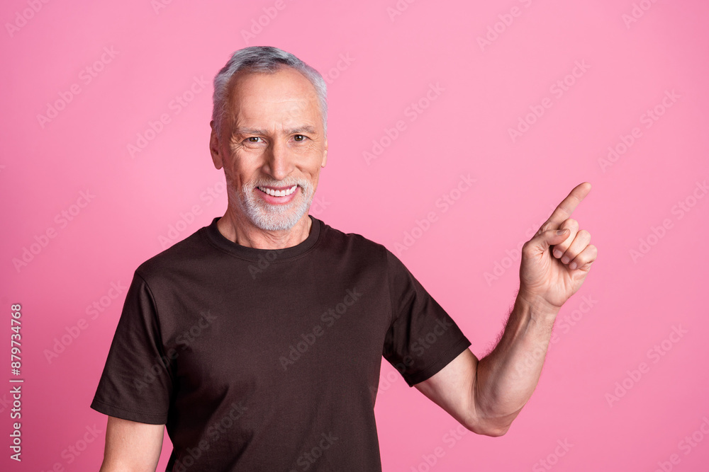 Portrait of cheerful man with white gray beard dressed brown t-shirt directing at promo empty space isolated on pink color background
