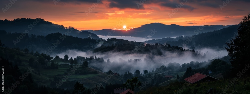 The sun sets over fog-shrouded mountains, valley below filled with houses The sun sets over fog-shrouded mountains, valley below filled with houses
