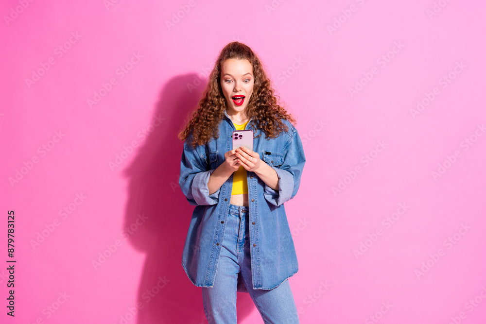 Photo of impressed positive girl wear jeans shirt typing apple iphone samsung device empty space isolated pink color background Photo of impressed positive girl wear jeans shirt typing apple iphone samsung device empty space isolated pink color background