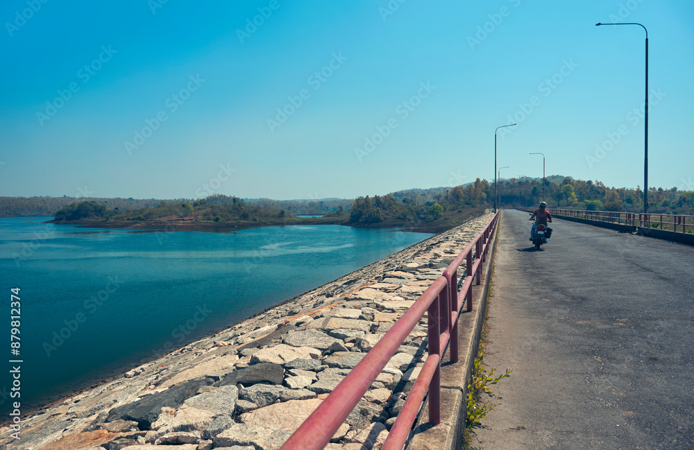 Obraz premium long stretch of dike road on Purulia pumped storage project (upper dam) in the vicinity of Ajodhya Hills. Set against backdrop of serene nature, the dam is a popular travel destination in Purulia.