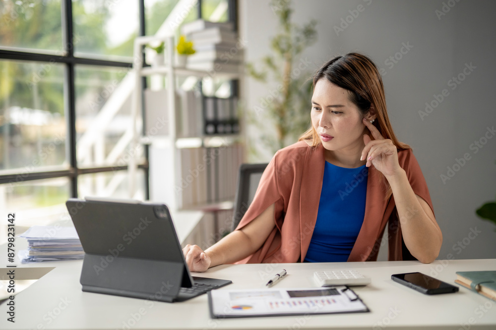 A woman is sitting at a desk with a laptop and a keyboard