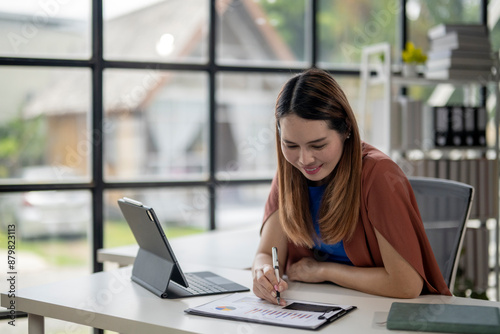 A woman is sitting at a desk with a laptop and a piece of paper Free Download A woman is sitting at a desk with a laptop and a piece of paper - GFXLoad