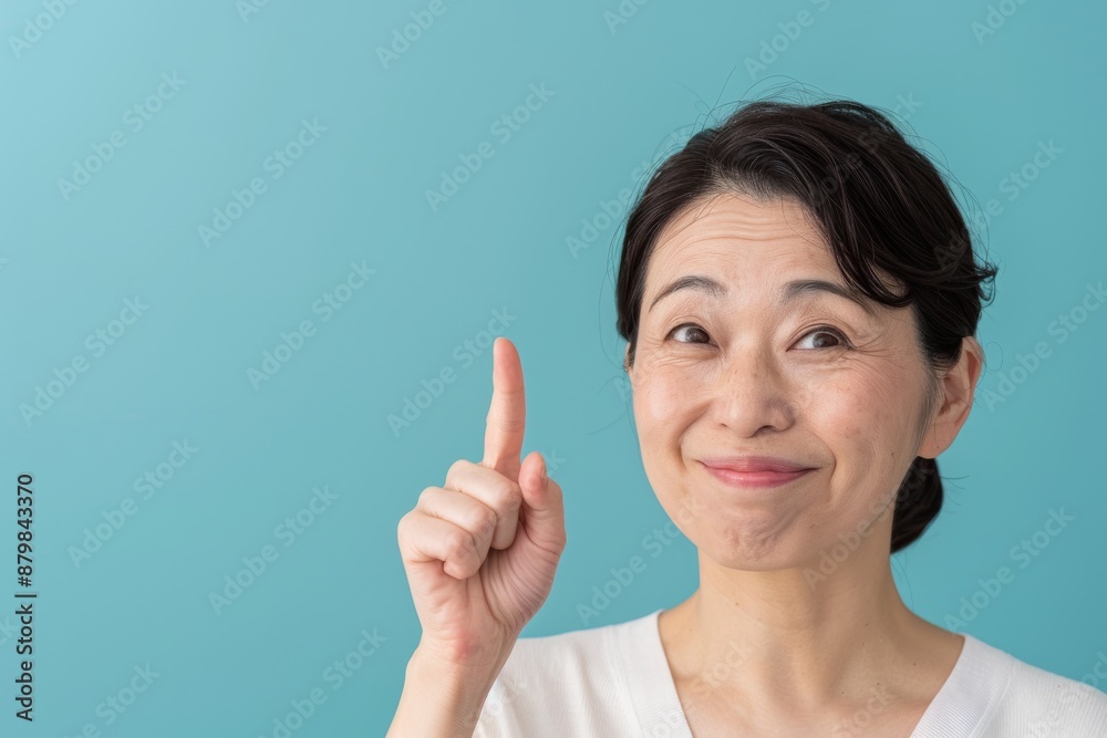 Skincare with pretty Asian Korean beauty woman pointing finger short hair, makeup glowing face and healthy facial skin portrait smile on isolated blue background. Skincare with pretty Asian Korean beauty woman pointing finger short hair, makeup glowing face and healthy facial skin portrait smile on isolated blue background.