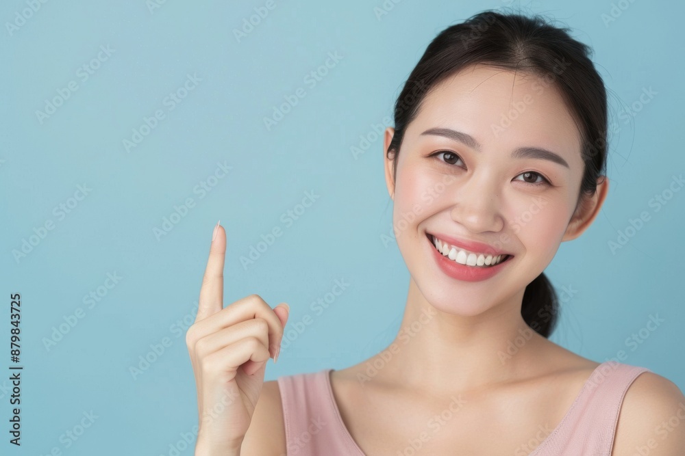 Skincare with pretty Asian Korean beauty woman pointing finger short hair, makeup glowing face and healthy facial skin portrait smile on isolated blue background. Skincare with pretty Asian Korean beauty woman pointing finger short hair, makeup glowing face and healthy facial skin portrait smile on isolated blue background.