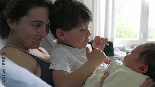 Mother and older sibling gently admiring newborn baby in hospital bed. family moment emphasizes the warmth and connection between siblings and the loving care of the mother