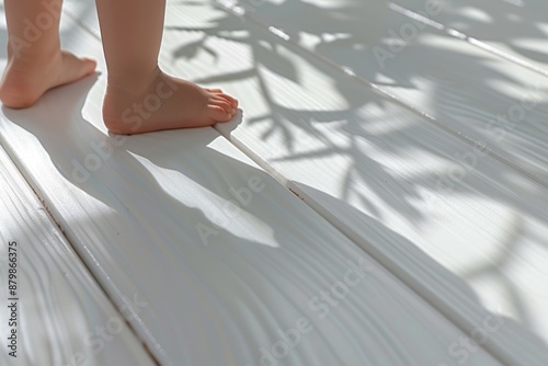 Close-up of tiny baby bare feet on a smooth white hardwood floor.