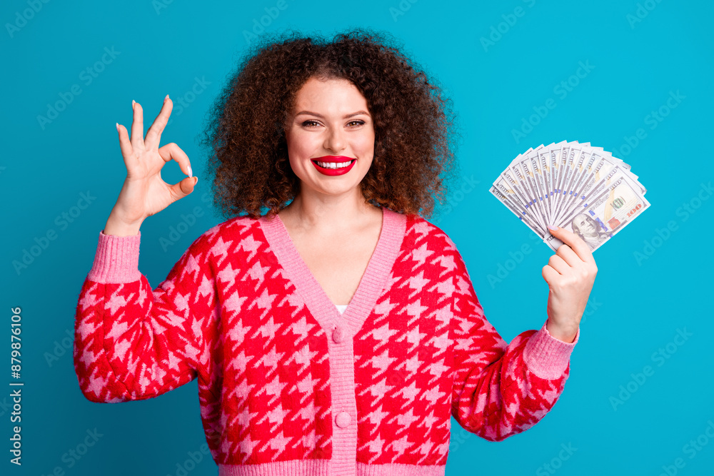 Photo of charming positive woman wear red cardigan rising cash fan showing okey isolated blue color background Photo of charming positive woman wear red cardigan rising cash fan showing okey isolated blue color background
