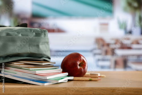 Back to school concept. Wooden desk top with backpack and apple and school stuff with blurred classroom backround  photo