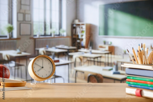 School desk and alarm clock and copy space for product in a big bright classroom interior. photo