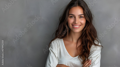 A happy young professional woman posing alone against a gray wall background © Desinage