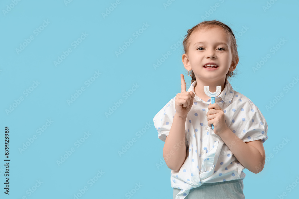 Happy cute little girl with toothbrush pointing at something on blue background Happy cute little girl with toothbrush pointing at something on blue background