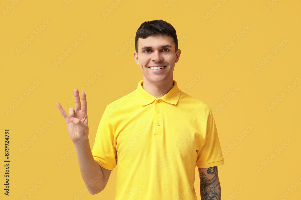 Young deaf mute man using sign language on yellow background Young deaf mute man using sign language on yellow background