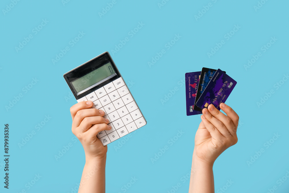 Female hands with credit cards and calculator on blue background Female hands with credit cards and calculator on blue background