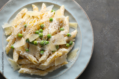 Delicious pasta with green peas, cheese and creamy sauce on grey table, top view