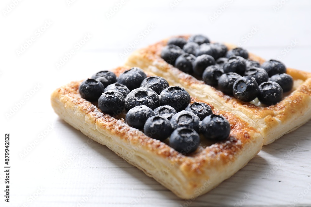Tasty puff pastries with blueberries on white wooden table, closeup Tasty puff pastries with blueberries on white wooden table, closeup