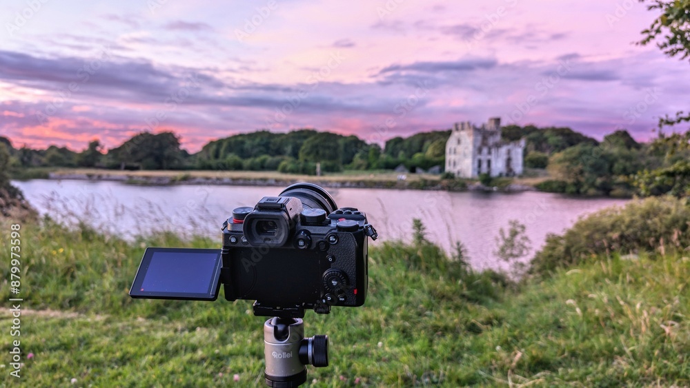 Closeup of modern mirrorless dslr camera recording beautiful scene of Meno
castle at sunset at Galway, ireland, technology concept background
